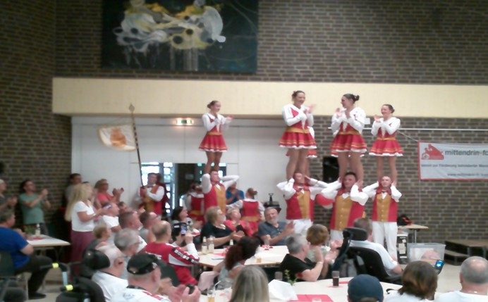 Eine Gruppe von Tänzern in festlicher Kleidung führt eine Choreografie vor.
