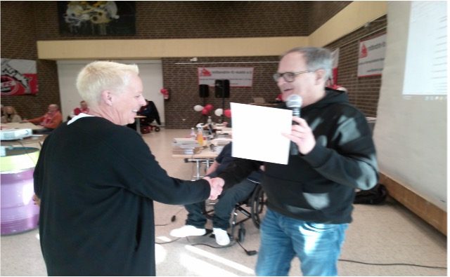 Eine Person überreicht ein Dokument an eine andere Person bei einer Veranstaltung.