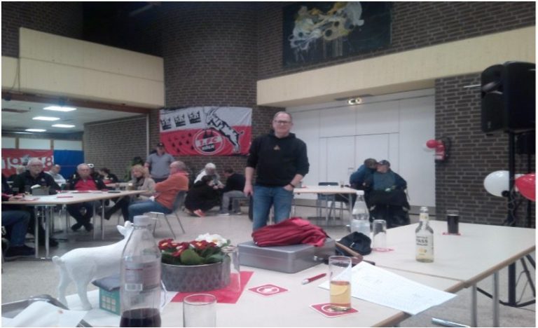 Zwei Männer halten einen großen Scheck in einem festlichen Umfeld.